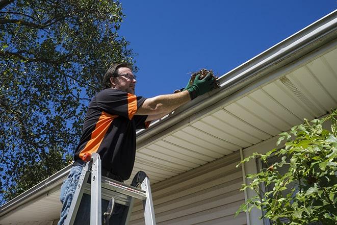 a skilled worker fixing broken gutter on a roof in Ballwin